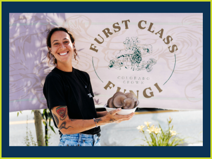 A woman presents a bowl of food in front of a sign reading "First Class Fungi," showcasing a culinary experience.