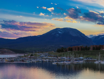 A serene lake with boats floating, surrounded by majestic mountains in the background.