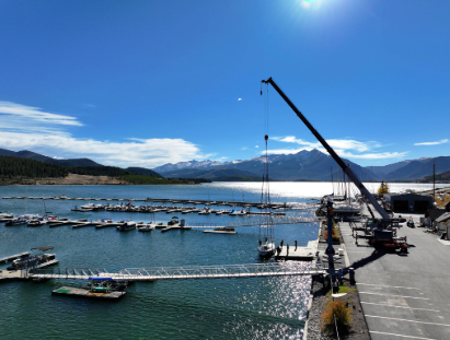 A crane is lifting a boat into the water at a dock, showcasing the process of launching a vessel.