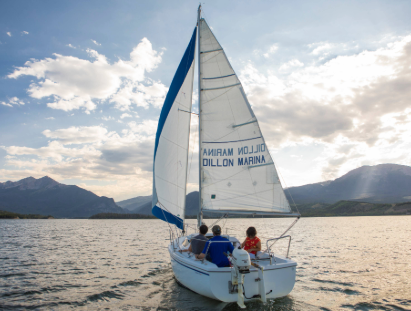 A couple enjoys sailing on a sailboat, gliding across the calm water under a clear sky