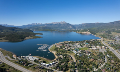 Aerial view showcasing a serene lake surrounded by majestic mountains under a clear blue sky