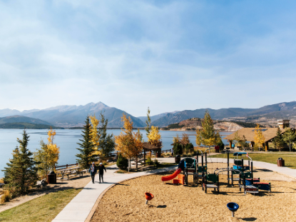 A playground surrounded by a lake, with mountains rising majestically in the background