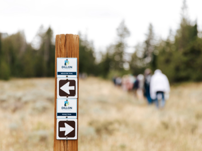 A wooden post sign with multiple arrows indicating different directions