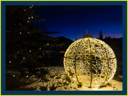 A colorful Christmas light ball resting on a blanket of fresh snow, creating a festive winter scene.