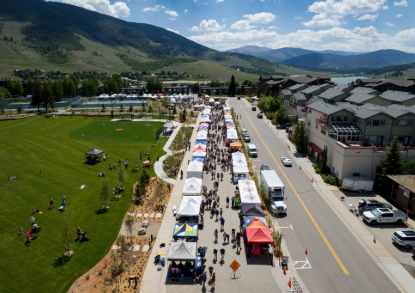A bustling town square filled with tents and people enjoying the vibrant atmosphere of a community event.