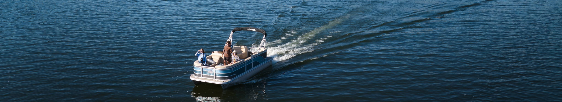 A man navigates a boat across the water, creating ripples in the calm surface.