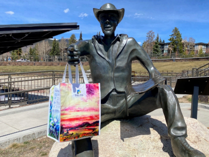 A statue of a man holds a reusable bag with vibrant colors